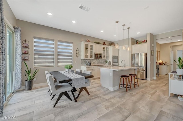 9940 Heather Moore Ave, Las Vegas, NV 89166 - kitchen with stainless steel appliances, an island with sink, a breakfast bar, light countertops, and white cabinets