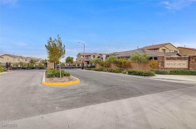 9940 Heather Moore Ave, Las Vegas, NV 89166 - view of asphalt road featuring street lights, a gate, a residential view, sidewalks, and a gated entry