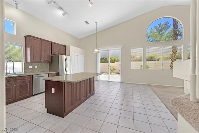 20 Staghorn St, Henderson, NV 89012 - kitchen featuring appliances with stainless steel finishes, light tile patterned floors, high vaulted ceiling, a center island, and pendant lighting