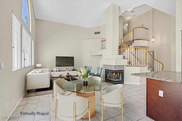 20 Staghorn St, Henderson, NV 89012 - dining space featuring a towering ceiling, light tile patterned floors, stairs, and a tile fireplace
