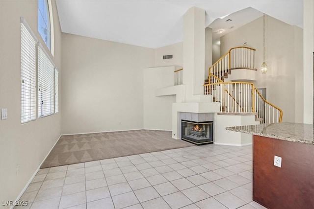 20 Staghorn St, Henderson, NV 89012 - unfurnished living room featuring stairs, a high ceiling, light carpet, light tile patterned floors, and a tiled fireplace