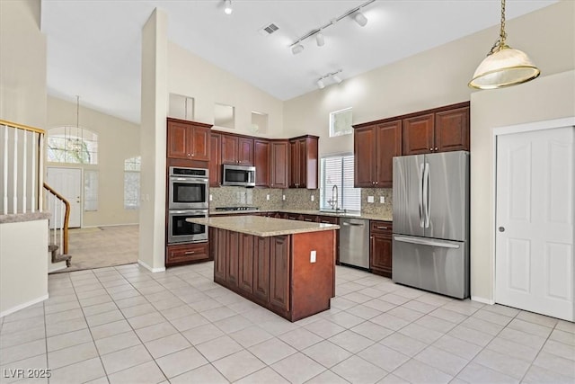 20 Staghorn St, Henderson, NV 89012 - kitchen featuring appliances with stainless steel finishes, a kitchen island, light tile patterned floors, tasteful backsplash, and pendant lighting