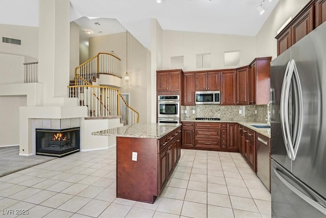 20 Staghorn St, Henderson, NV 89012 - kitchen featuring appliances with stainless steel finishes, light tile patterned floors, backsplash, high vaulted ceiling, and light stone counters
