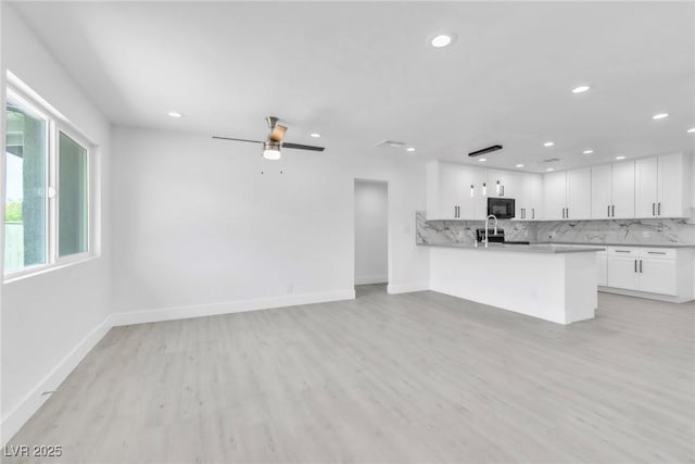 244 N 19th St, Las Vegas, NV 89101 - kitchen featuring recessed lighting, light wood-style flooring, black microwave, white cabinets, and tasteful backsplash