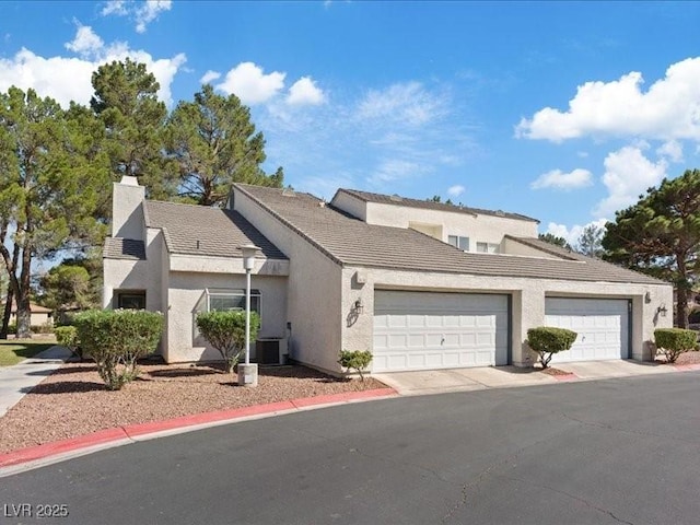 8961 Clairton Ct, Las Vegas, NV 89117 - view of front facade with stucco siding, an attached garage, a chimney, a tiled roof, and driveway