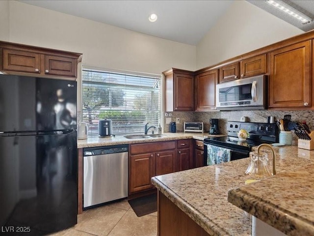 8961 Clairton Ct, Las Vegas, NV 89117 - kitchen with black appliances, backsplash, light tile patterned flooring, lofted ceiling, and light stone countertops