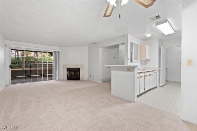 2200 S Fort Apache Rd Unit 1114, Las Vegas, NV 89117 - unfurnished living room featuring light colored carpet, a textured ceiling, a ceiling fan, a tile fireplace, and light tile patterned flooring