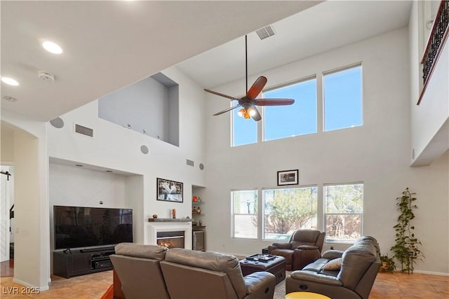 10500 Eagle Nest St, Las Vegas, NV 89141 - living room with ceiling fan, healthy amount of natural light, a high ceiling, a warm lit fireplace, and recessed lighting