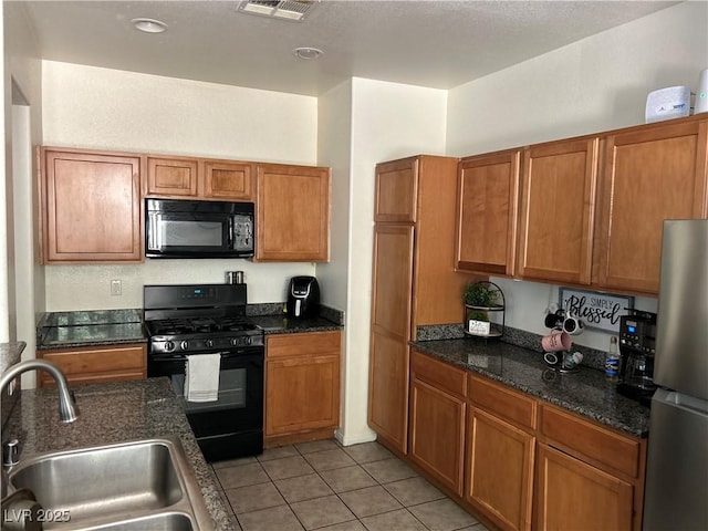 4013 Kindhearted Ct, North Las Vegas, NV 89032 - kitchen featuring black appliances, brown cabinets, light tile patterned floors, and dark stone countertops