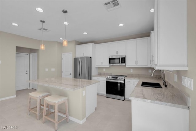 7104 Stockton Dunes St, North Las Vegas, NV 89084 - kitchen featuring appliances with stainless steel finishes, a center island, light stone countertops, white cabinetry, and recessed lighting