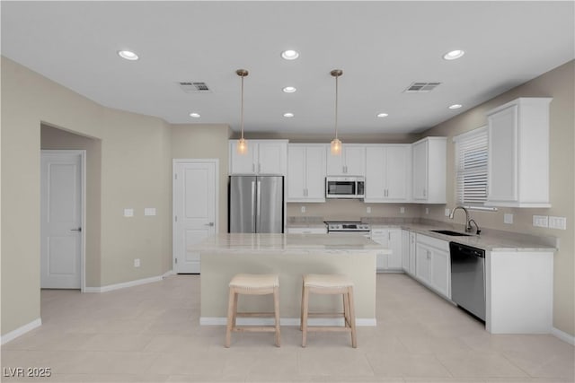 7104 Stockton Dunes St, North Las Vegas, NV 89084 - kitchen with appliances with stainless steel finishes, white cabinets, a center island, recessed lighting, and light countertops