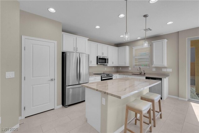 7104 Stockton Dunes St, North Las Vegas, NV 89084 - kitchen with appliances with stainless steel finishes, recessed lighting, white cabinetry, a kitchen island, and light stone counters
