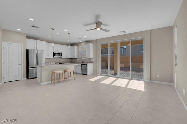 7104 Stockton Dunes St, North Las Vegas, NV 89084 - kitchen featuring appliances with stainless steel finishes, a ceiling fan, a breakfast bar, white cabinetry, and a kitchen island