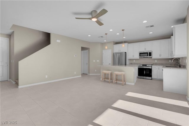 7104 Stockton Dunes St, North Las Vegas, NV 89084 - kitchen featuring stainless steel appliances, ceiling fan, a kitchen island, a kitchen bar, and light countertops