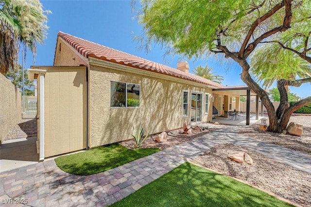 1734 Marshall Dr, Henderson, NV 89014 - back of property with a chimney, stucco siding, a patio, and a tiled roof