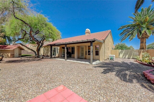 1734 Marshall Dr, Henderson, NV 89014 - rear view of house featuring a chimney, a storage unit, a tiled roof, stucco siding, and a patio