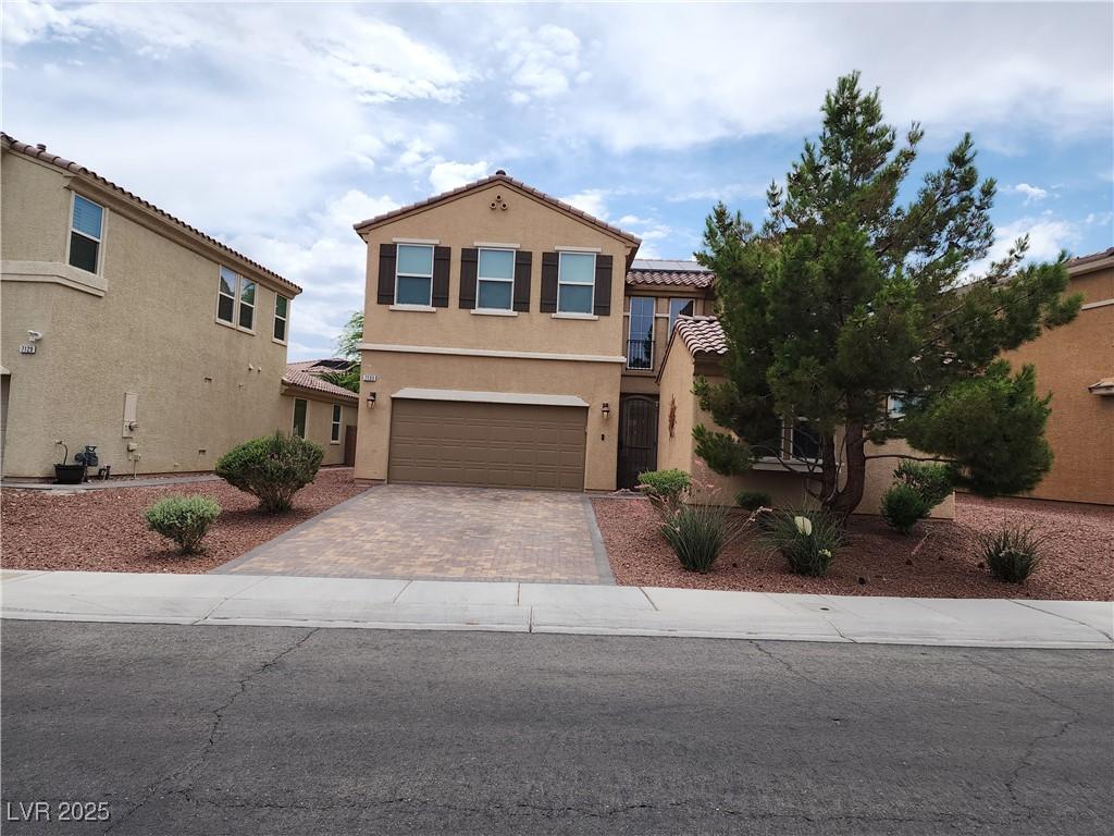7133 Weavers Pl, North Las Vegas, NV 89084 - view of front of house featuring decorative driveway, stucco siding, a tile roof, and a garage