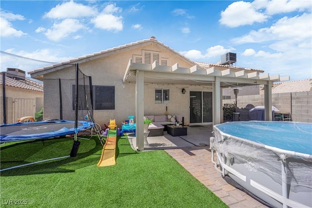 7316 Young Doe Ave, Las Vegas, NV 89130 - rear view of house featuring a trampoline, stucco siding, a patio area, a pergola, and an outdoor living space