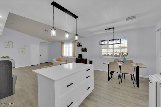 7316 Young Doe Ave, Las Vegas, NV 89130 - kitchen featuring light wood finished floors, light countertops, white cabinets, pendant lighting, and vaulted ceiling
