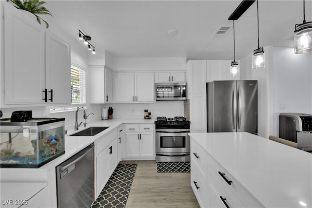 7316 Young Doe Ave, Las Vegas, NV 89130 - kitchen featuring stainless steel appliances, white cabinets, light wood-style floors, and decorative light fixtures