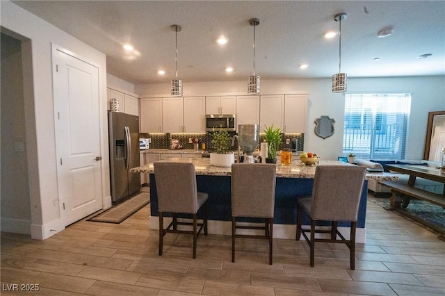 9584 Jadeite Ln, Las Vegas, NV 89143 - kitchen with stainless steel appliances, white cabinets, light wood finished floors, tasteful backsplash, and recessed lighting