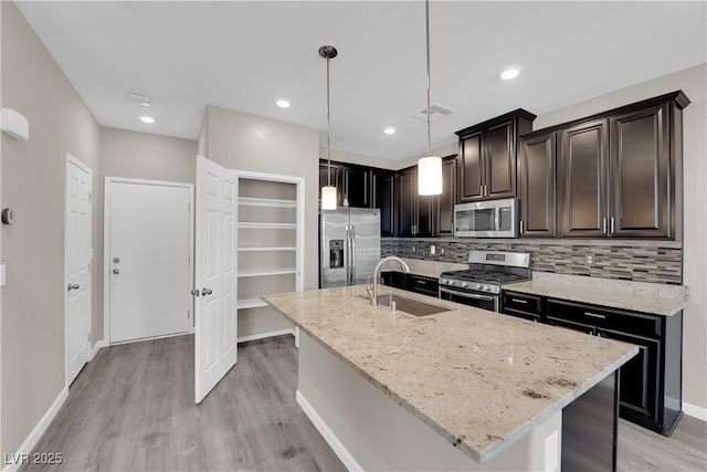 8520 Insignia Ave Unit 104, Las Vegas, NV 89178 - kitchen with appliances with stainless steel finishes, light wood-style floors, light stone countertops, tasteful backsplash, and a kitchen island with sink