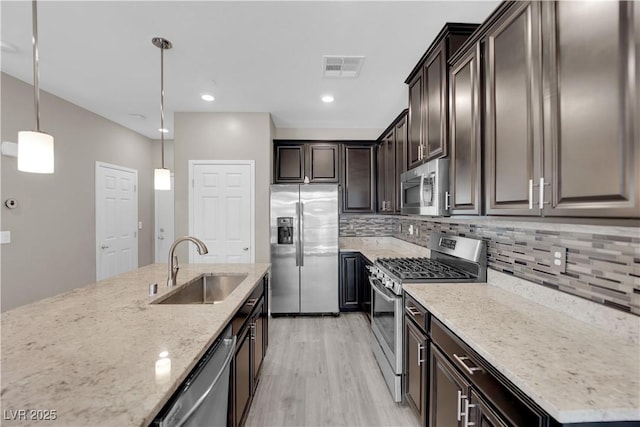 8520 Insignia Ave Unit 104, Las Vegas, NV 89178 - kitchen featuring appliances with stainless steel finishes, light stone countertops, light wood-style flooring, dark brown cabinetry, and tasteful backsplash