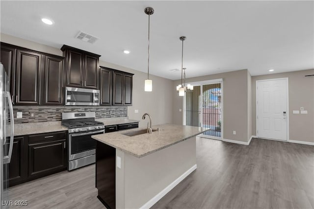 8520 Insignia Ave Unit 104, Las Vegas, NV 89178 - kitchen featuring stainless steel appliances, light wood-style floors, decorative backsplash, a chandelier, and light stone countertops