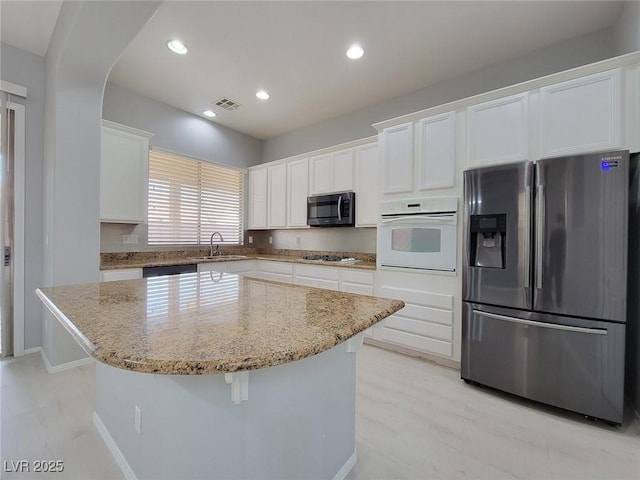 10482 Calico Pines Ave, Las Vegas, NV 89135 - kitchen with stainless steel fridge with ice dispenser, white oven, gas stovetop, light stone countertops, and white cabinetry