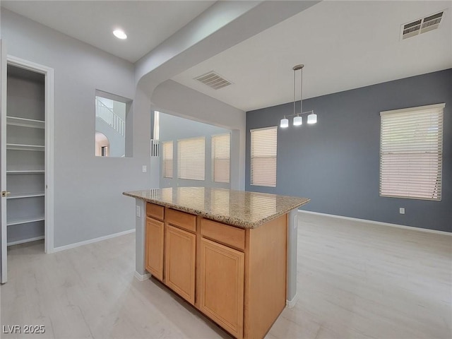 10482 Calico Pines Ave, Las Vegas, NV 89135 - kitchen featuring a center island, light stone countertops, light wood-style floors, hanging light fixtures, and healthy amount of natural light