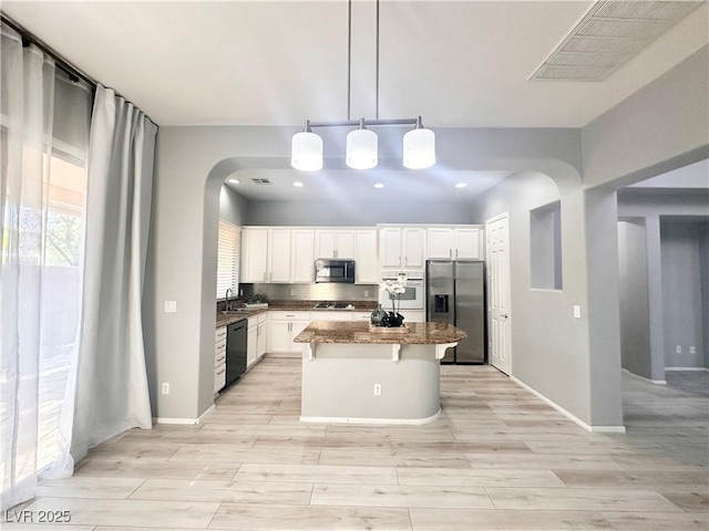 10482 Calico Pines Ave, Las Vegas, NV 89135 - kitchen with stainless steel fridge, dishwasher, arched walkways, a kitchen island, and light wood-type flooring