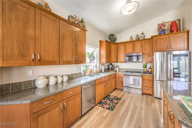3324 Canyon Lake Dr, Las Vegas, NV 89117 - kitchen featuring stainless steel appliances, light wood-style floors, lofted ceiling, brown cabinets, and stone countertops
