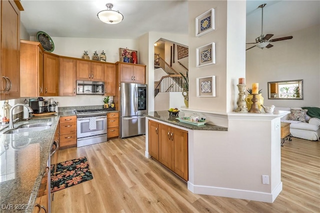 3324 Canyon Lake Dr, Las Vegas, NV 89117 - kitchen with stainless steel appliances, light wood finished floors, brown cabinets, and dark stone counters