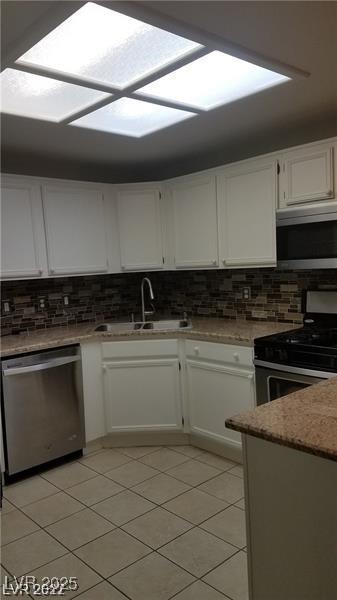 9470 Peace Way Unit 206, Las Vegas, NV 89147 - kitchen featuring appliances with stainless steel finishes, white cabinets, backsplash, and light tile patterned floors