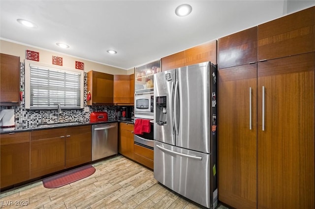 4544 Plaza De Vista St, Las Vegas, NV 89120 - kitchen featuring stainless steel appliances, dark countertops, decorative backsplash, brown cabinetry, and light wood-style floors