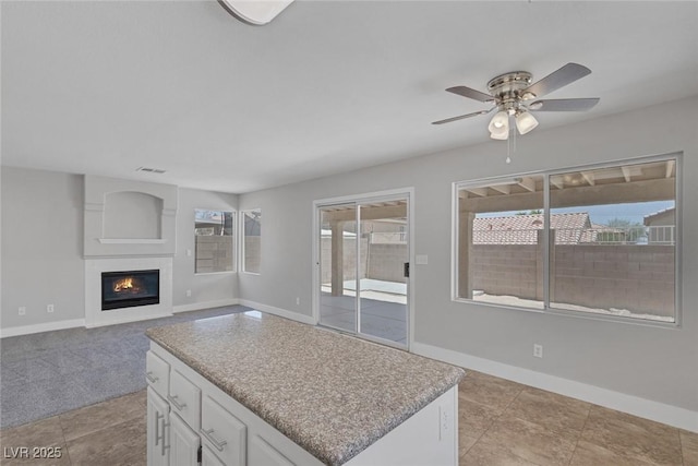 3664 Summer Picnic Ct, Las Vegas, NV 89147 - kitchen with plenty of natural light, ceiling fan, white cabinets, and a glass covered fireplace
