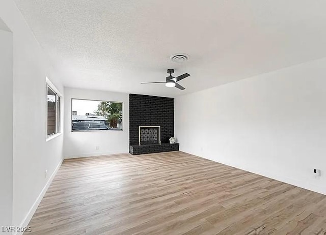 5321 Westleigh Ave, Las Vegas, NV 89146 - unfurnished living room with ceiling fan, light wood-style flooring, a fireplace, and a textured ceiling