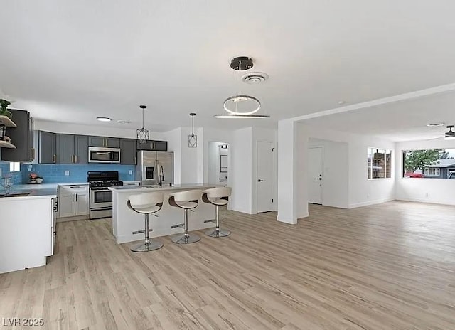 5321 Westleigh Ave, Las Vegas, NV 89146 - kitchen featuring stainless steel appliances, open floor plan, light wood-type flooring, light countertops, and a kitchen breakfast bar