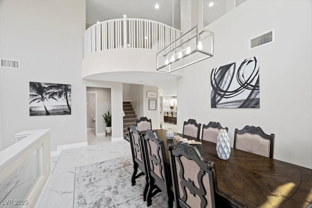 7012 Geese Gathering St, North Las Vegas, NV 89084 - dining room featuring marble look tile flooring, stairway, and a high ceiling