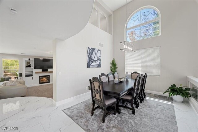 7012 Geese Gathering St, North Las Vegas, NV 89084 - dining area with marble tiled flooring, a glass covered fireplace, a chandelier, and a high ceiling