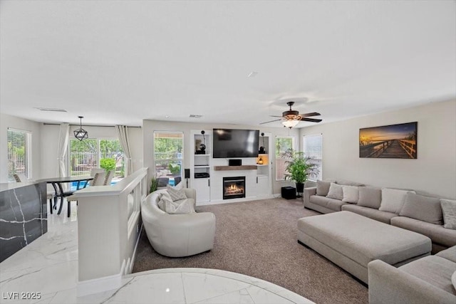 7012 Geese Gathering St, North Las Vegas, NV 89084 - living room featuring light marble finish flooring, a glass covered fireplace, and a ceiling fan