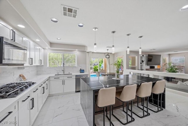 7012 Geese Gathering St, North Las Vegas, NV 89084 - kitchen with stainless steel appliances, light marble finish flooring, open floor plan, recessed lighting, and a kitchen bar