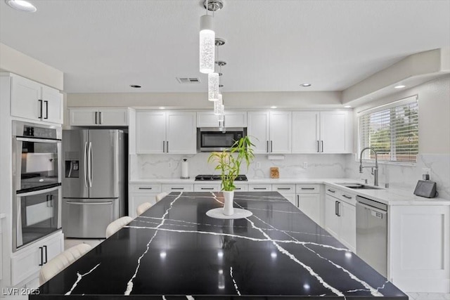 7012 Geese Gathering St, North Las Vegas, NV 89084 - kitchen with stainless steel appliances, white cabinetry, pendant lighting, and backsplash