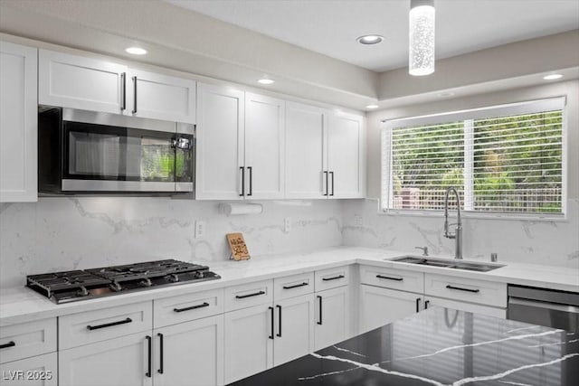 7012 Geese Gathering St, North Las Vegas, NV 89084 - kitchen with stainless steel appliances, white cabinets, recessed lighting, decorative backsplash, and light stone counters