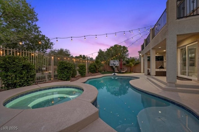 7012 Geese Gathering St, North Las Vegas, NV 89084 - pool at dusk with an in-ground hot tub, a fenced backyard, and a patio