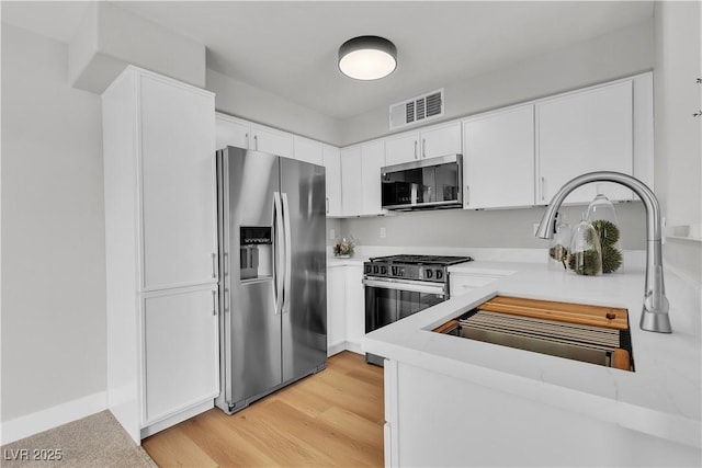 5710 E Tropicana Ave Unit 2152, Las Vegas, NV 89122 - kitchen featuring appliances with stainless steel finishes, light countertops, white cabinets, and light wood-style floors