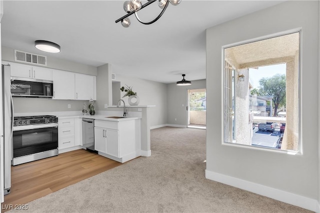 5710 E Tropicana Ave Unit 2152, Las Vegas, NV 89122 - kitchen with stainless steel appliances, light colored carpet, a peninsula, and white cabinets