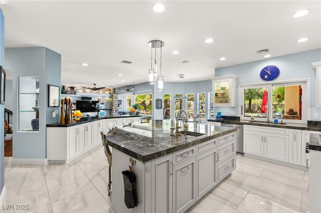 7428 Doe Ave, Las Vegas, NV 89117 - kitchen with dishwasher, a center island with sink, recessed lighting, light marble finish floors, and glass insert cabinets