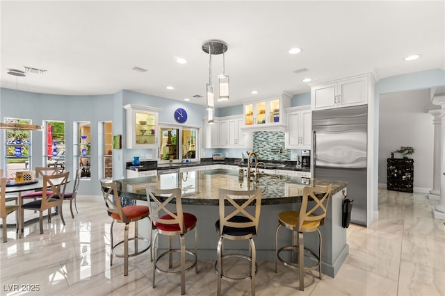 7428 Doe Ave, Las Vegas, NV 89117 - kitchen with built in fridge, decorative backsplash, plenty of natural light, an island with sink, and recessed lighting