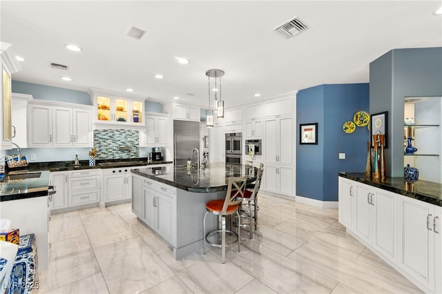 7428 Doe Ave, Las Vegas, NV 89117 - kitchen featuring light marble finish floors, backsplash, white cabinets, hanging light fixtures, and a breakfast bar